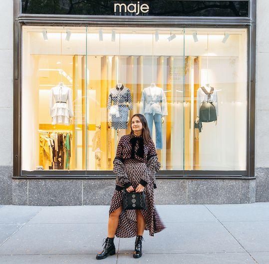 Woman standing in front of Maje in a matching skirt and blouse set