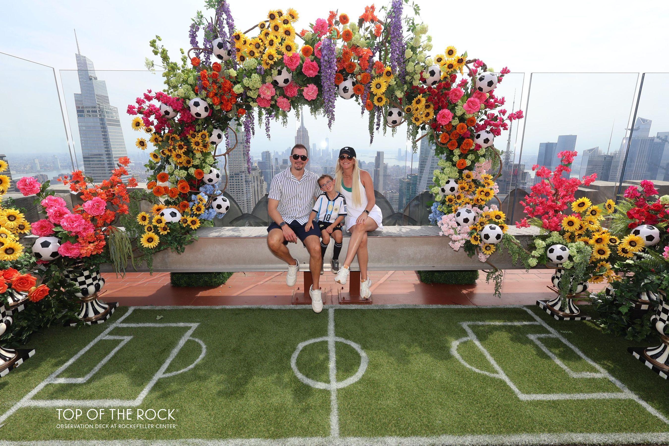 family smiling on the beam under a soccer flower arch