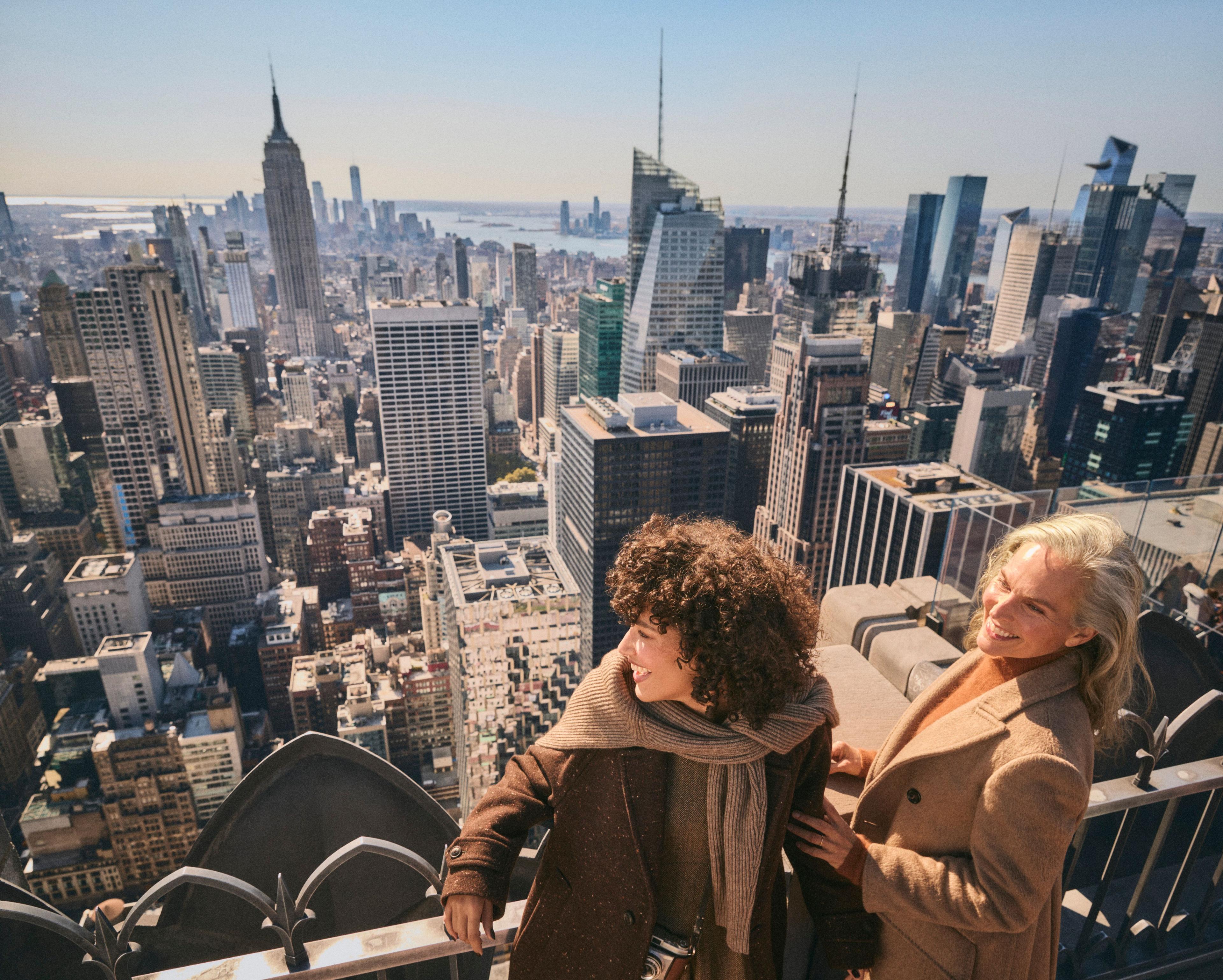 two women smiling looking out at the view of new york city