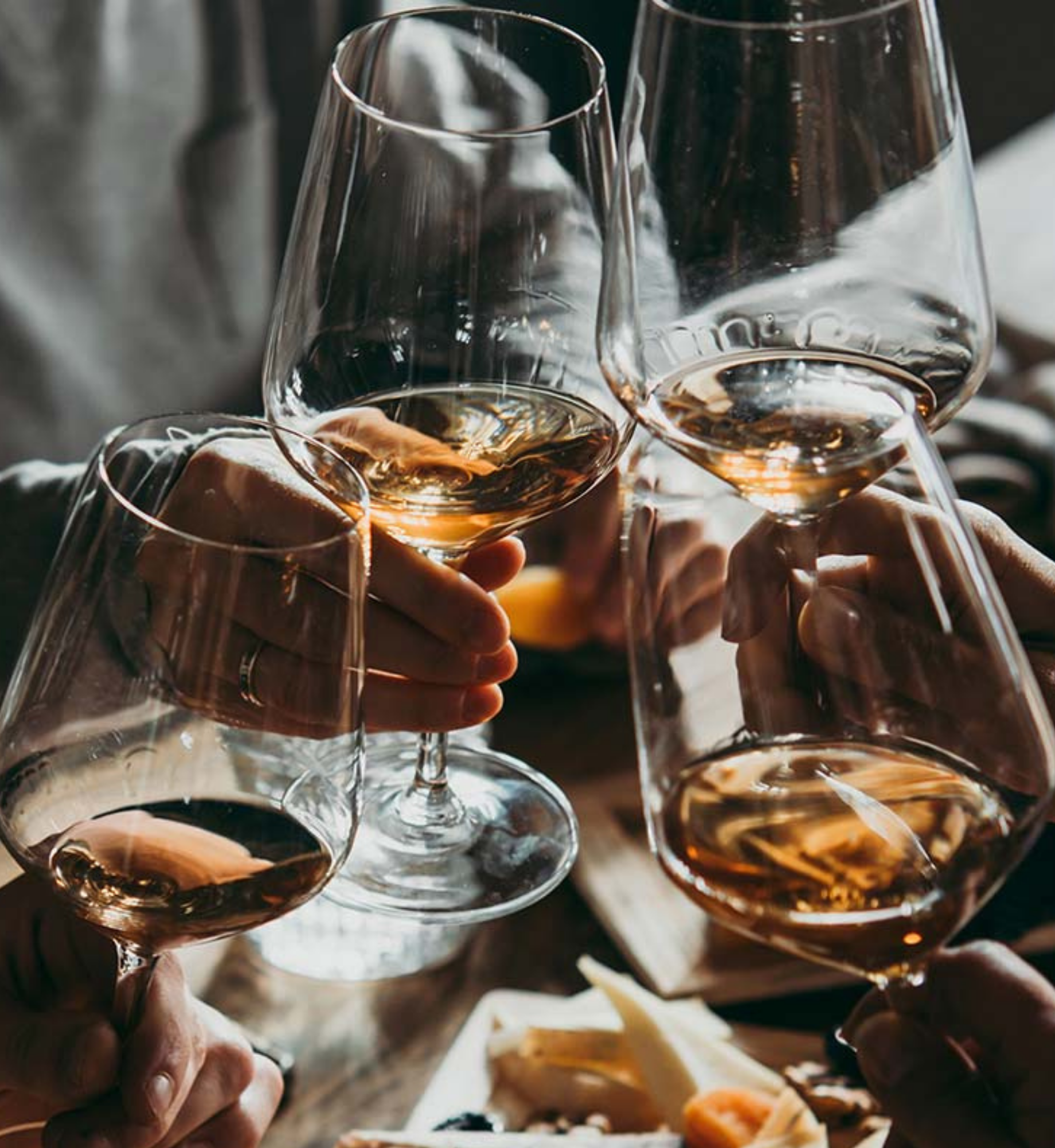 Four people cheersing with rose in wine glasses