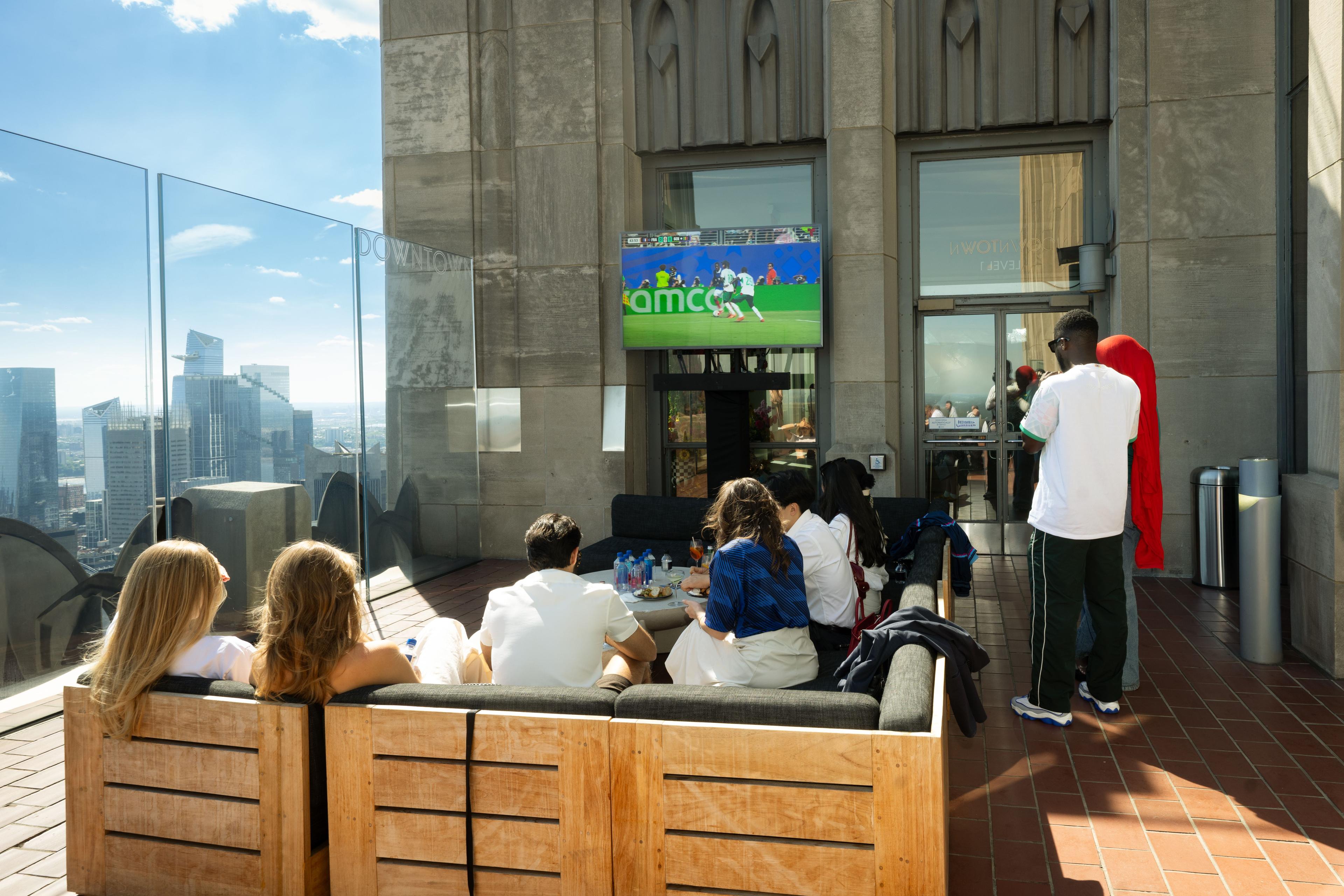 fans watching soccer at top of the rock