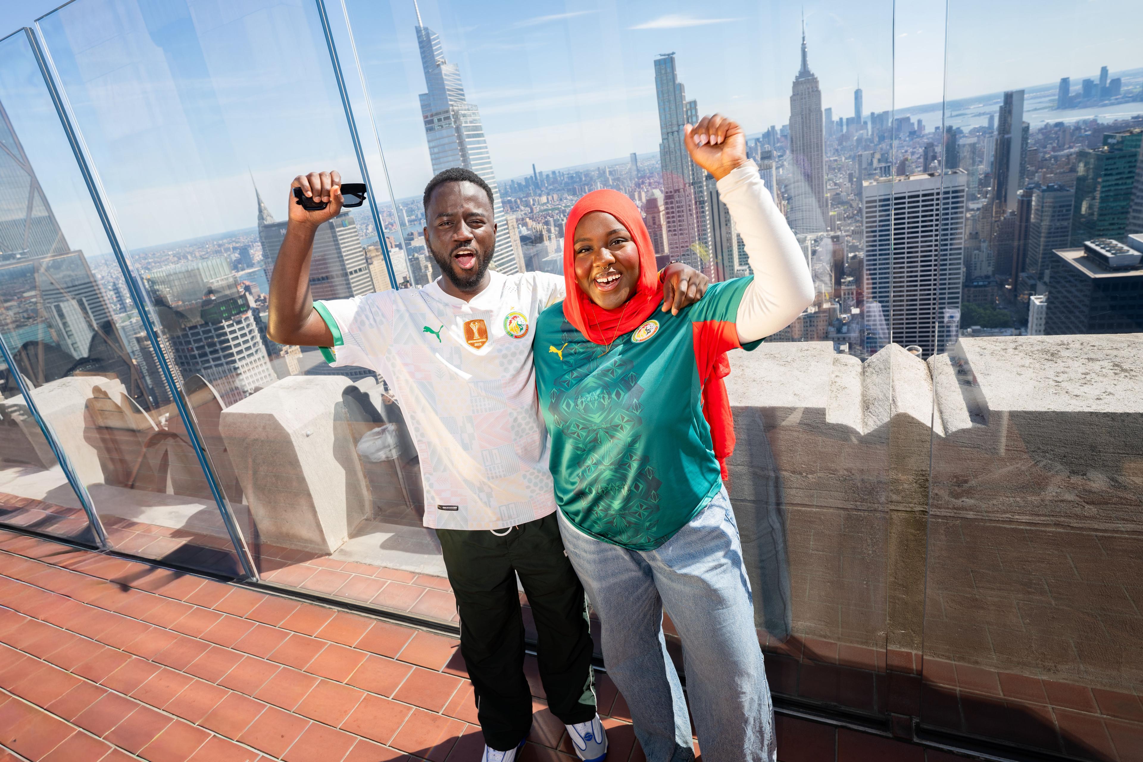 two soccer fans cheering at top of the rock