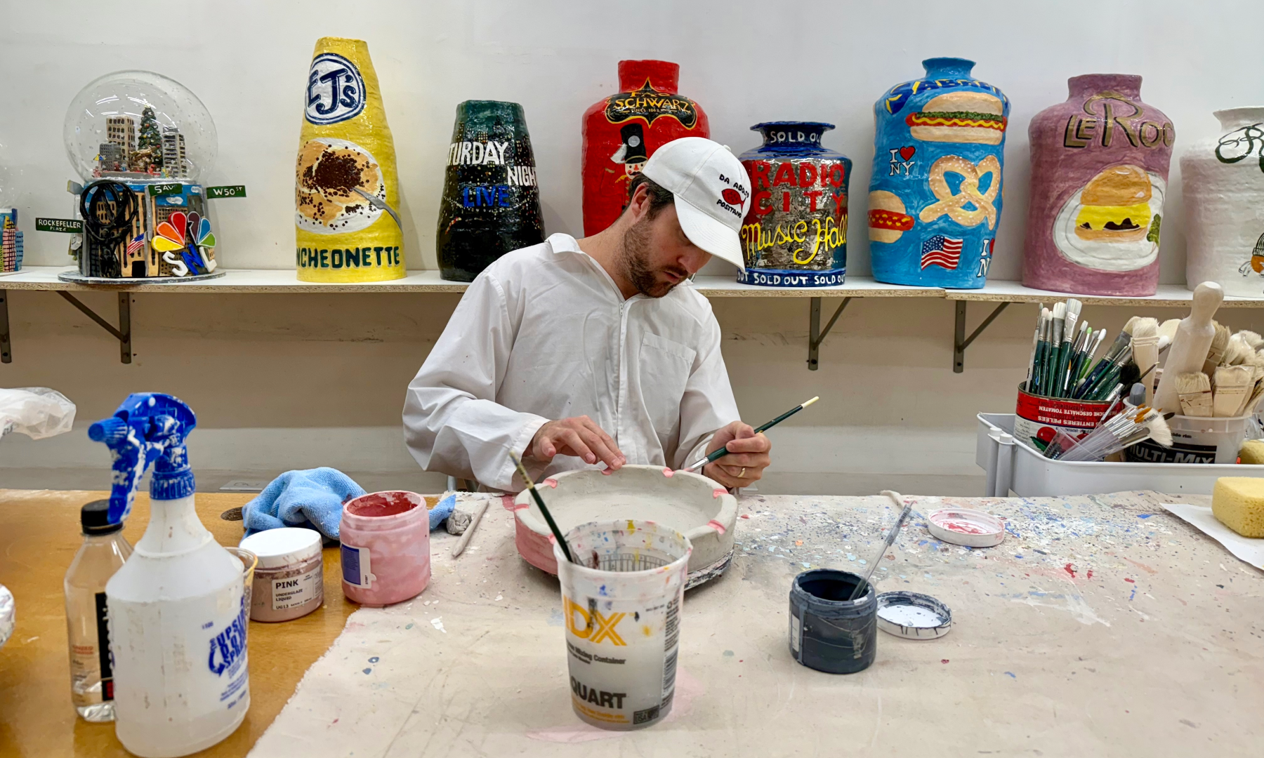 Artist Jake Clark painting a ceramic sculpture in his studio