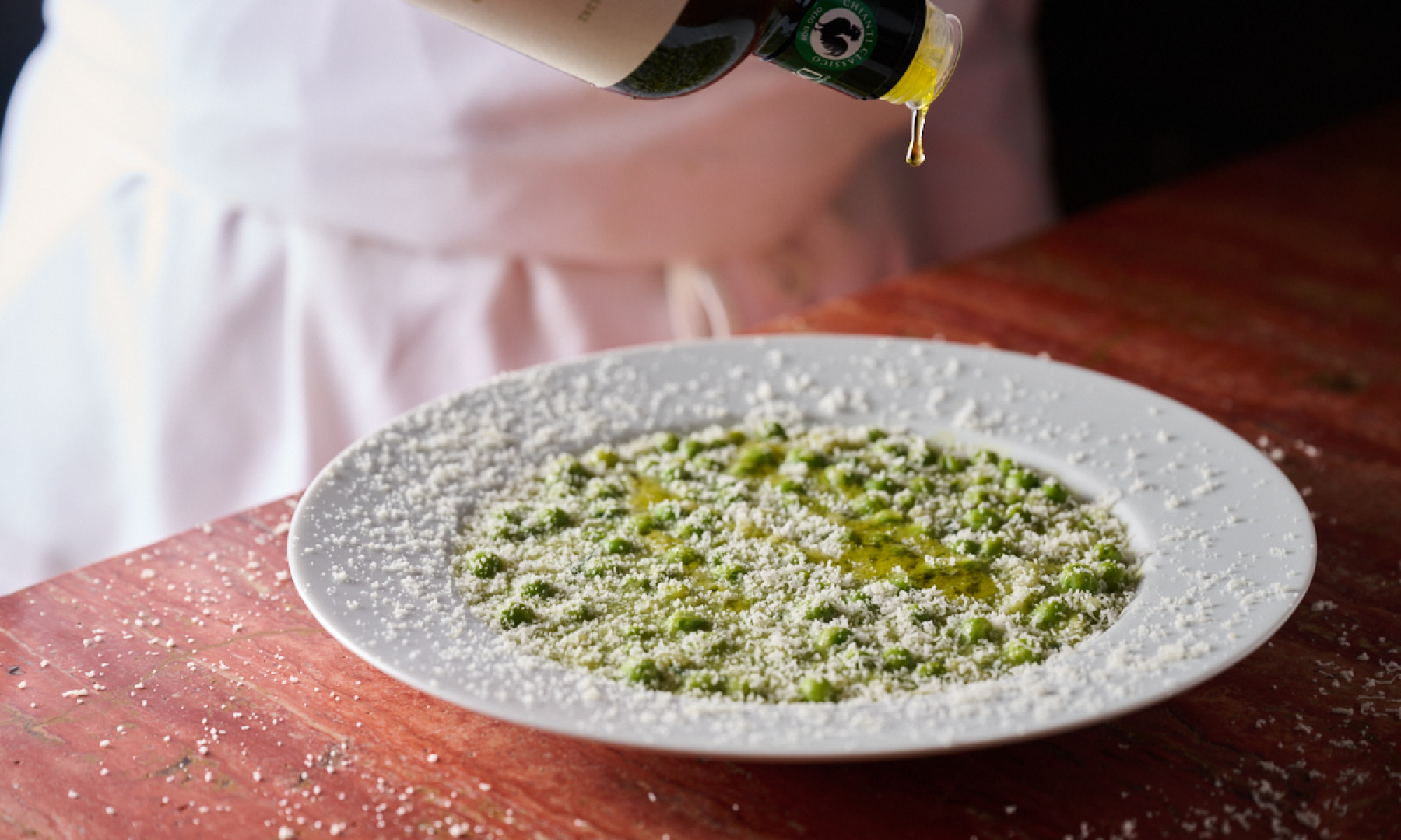A chef drizzling olive oil on a pasta dish from Jupiter at Rockefeller Center