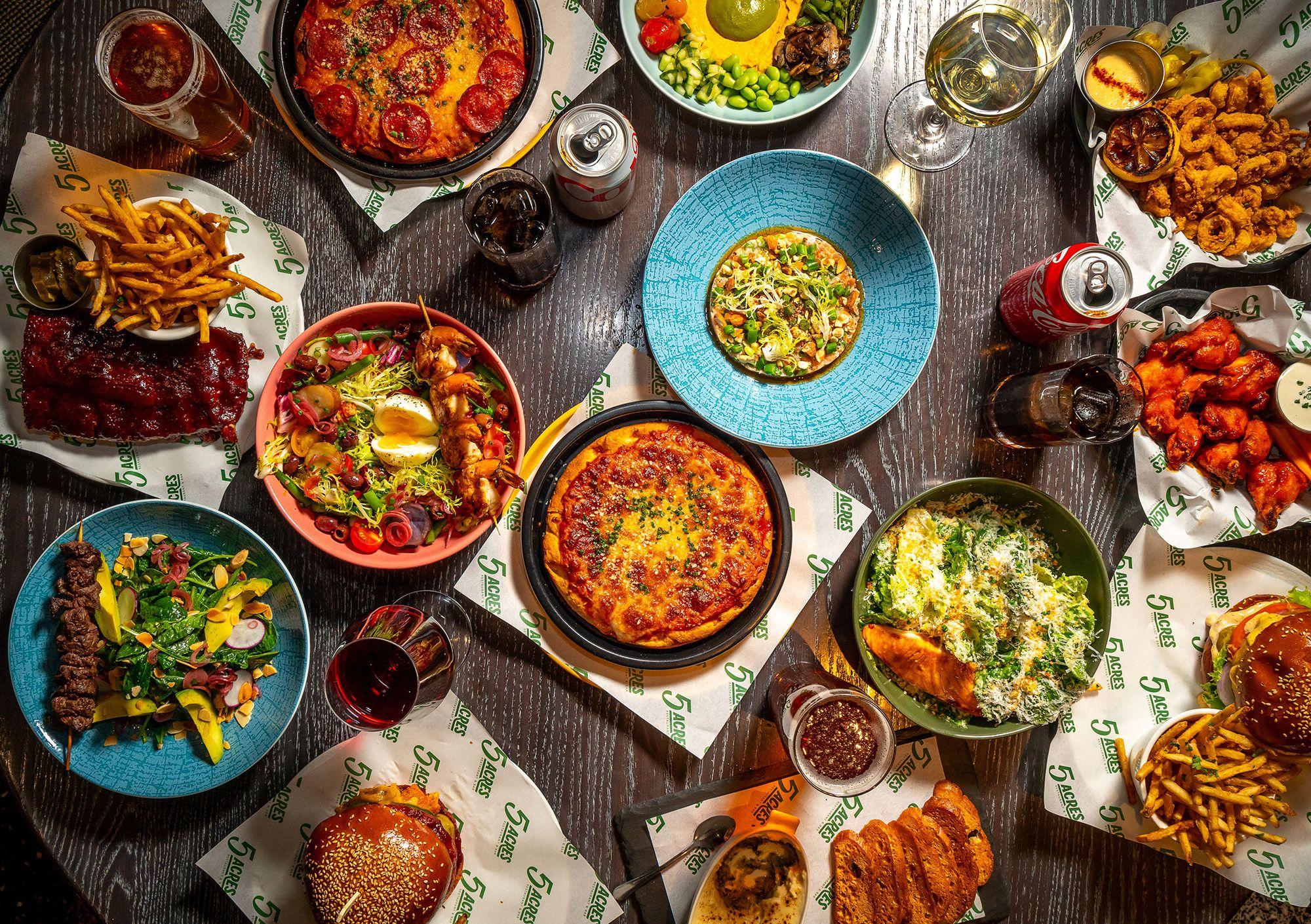 Multiple dishes of food on multi-colored plates from 5 Acres